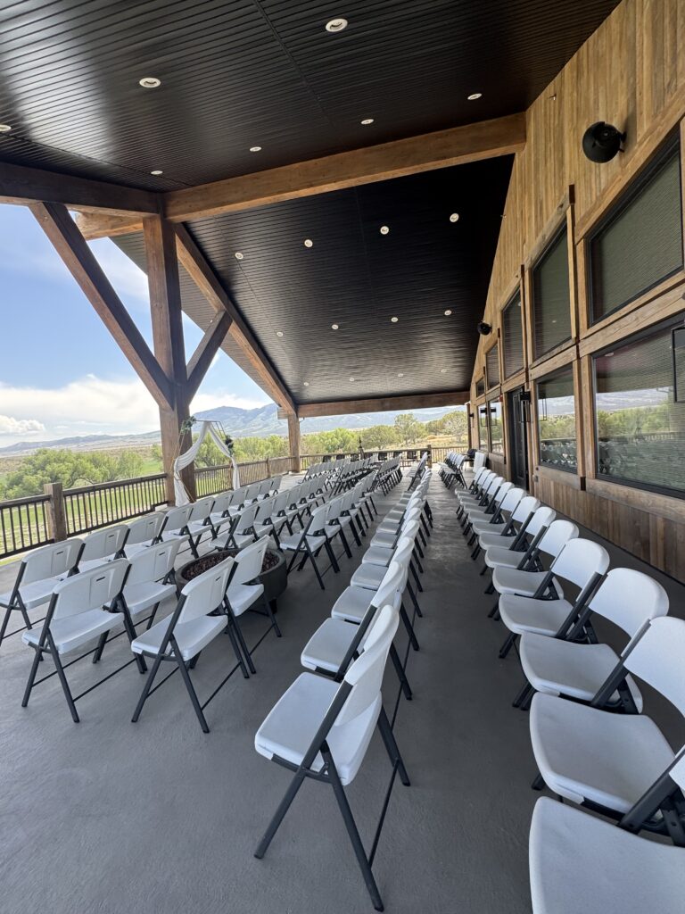 White chairs arranged for an outdoor wedding ceremony on the Elk Ridge Lodge balcony at Royal Creek Ranches.